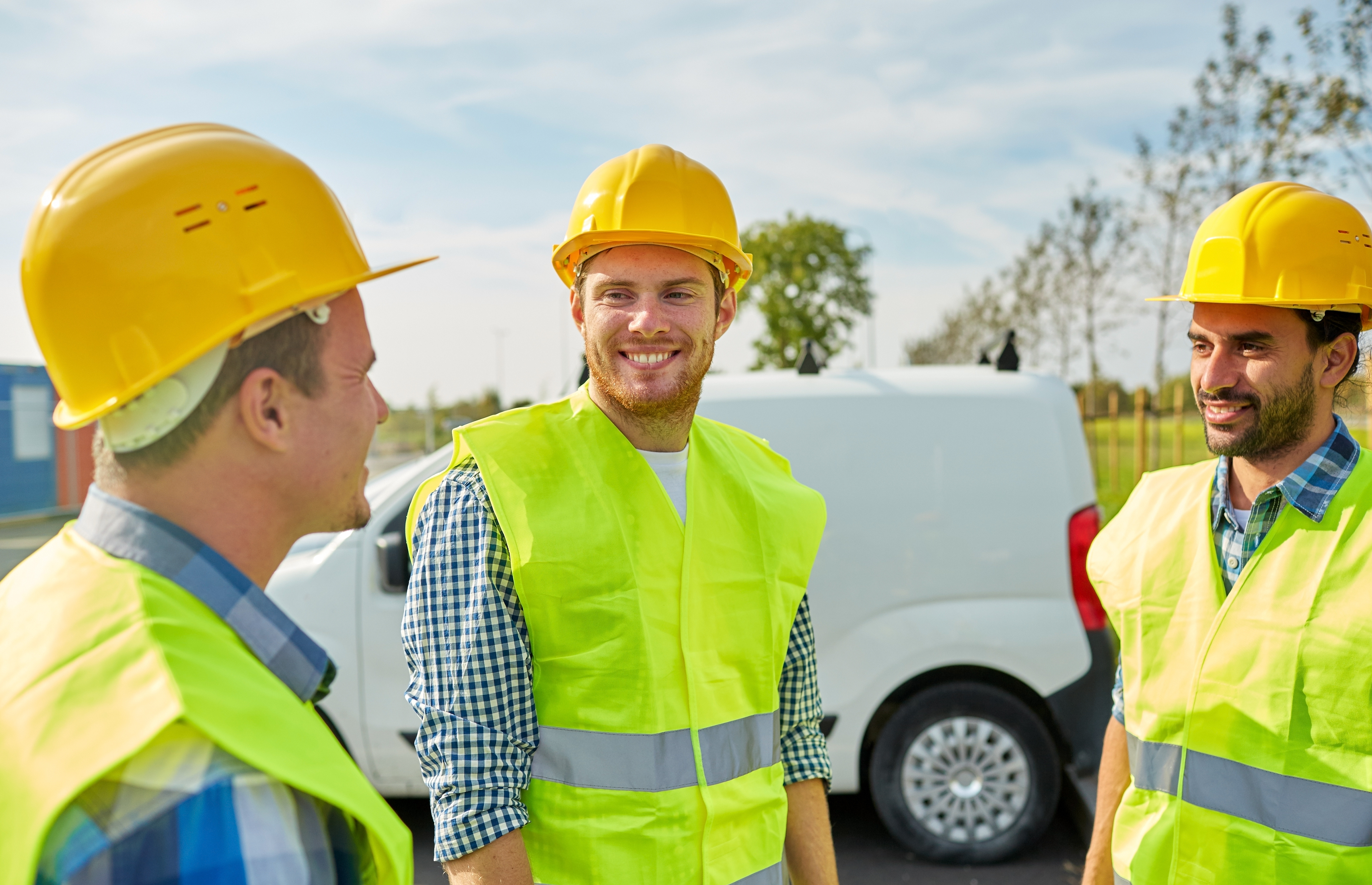 group of three contractors standing in front of vehicle