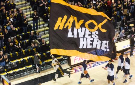 students waving large VCU flag at basketball game